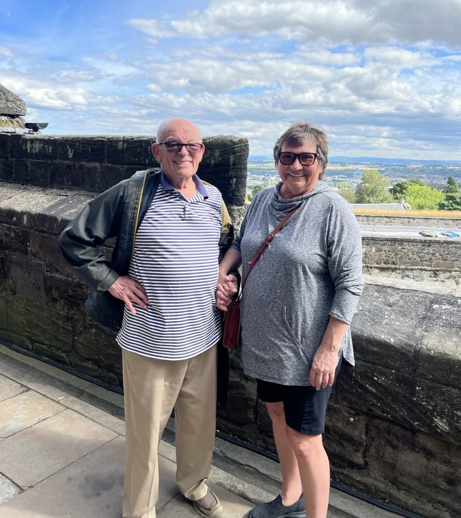 Scott and Kathy standing next to the rock wall overlooking the town of Stirling.