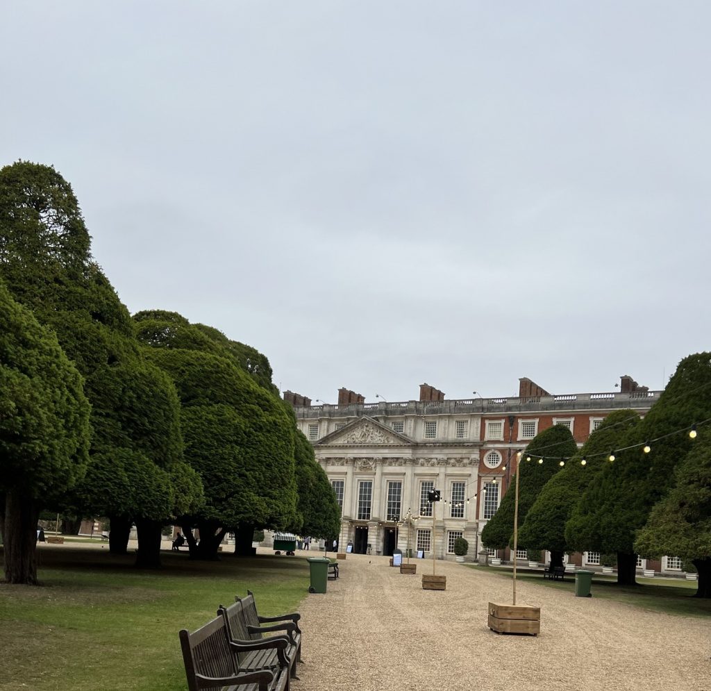 Exterior Garden with large evergreens trimmed in conical shapes. The trees line the walkway up to the palace.