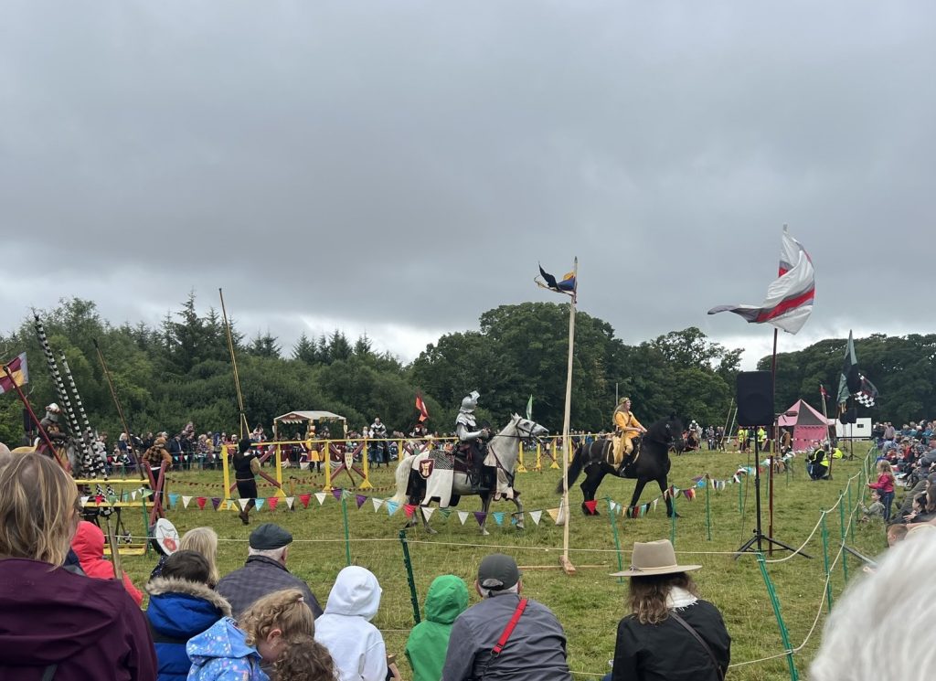 Jousting filed area with three people on horseback.
