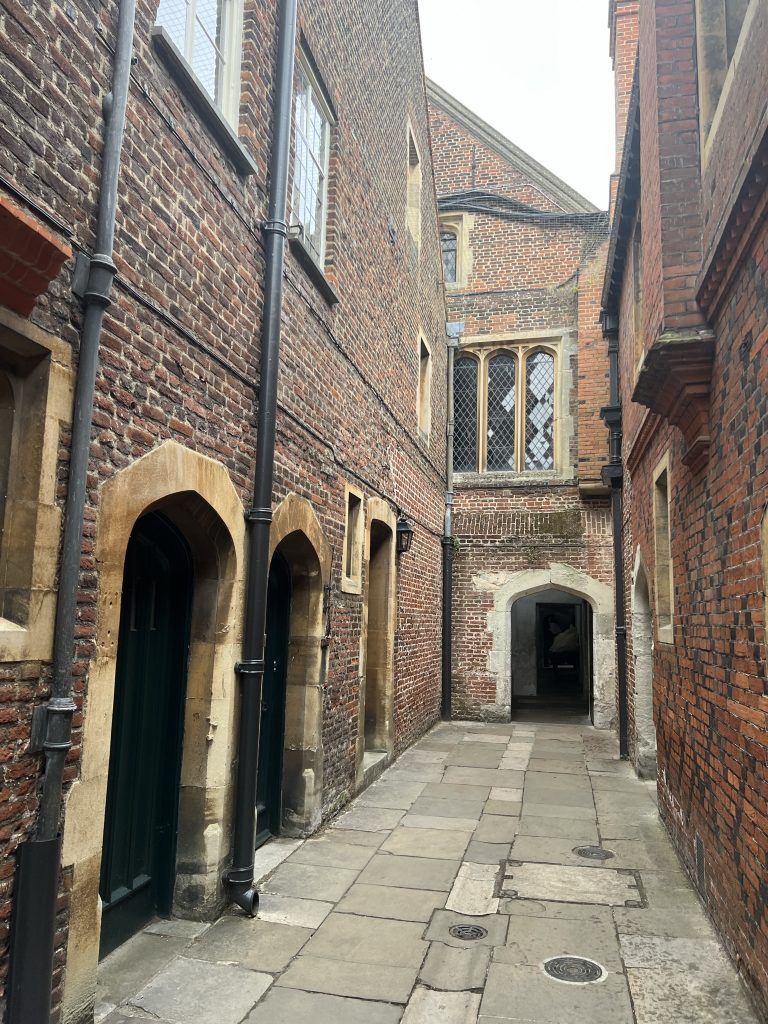 Alleyway leading between two areas of the Palace with red brick and four arched doorways leading into the grand kitchens.