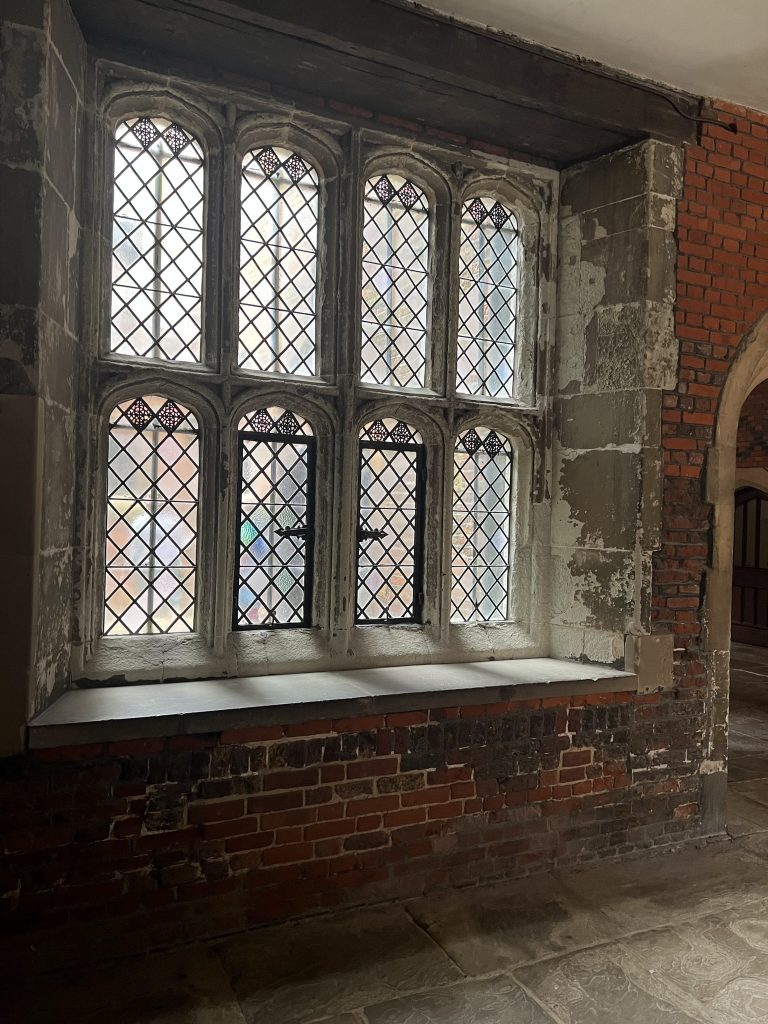Windows in classic Tudor style. Two rows of four small arched windows with the crisscross patterns. The lead making up the crisscross was used to hold the pieces of glass together.