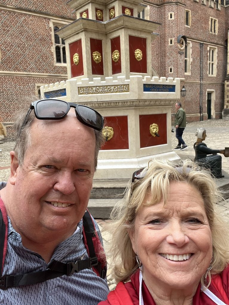 Kenny and Kay by the fountain in the courtyard. The fountain has been restored and is painted in bright marron colors with gold medallions. It is four section hig.