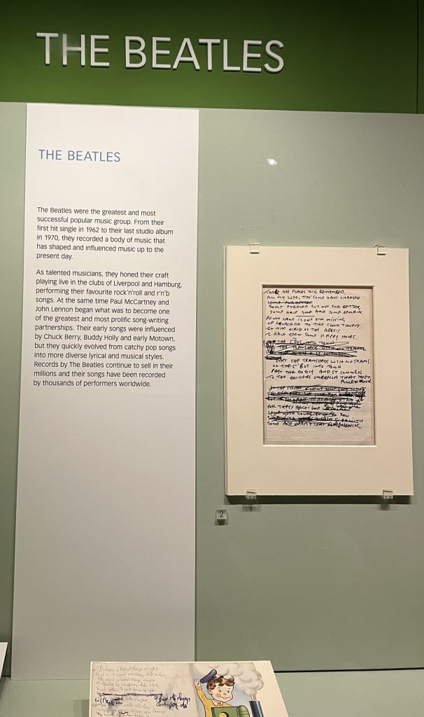 Display of Beatles including the handwritten lyrics to There Are Places I Remember with lines marked out and replaced. The lyrics to Hard Day's Night on the back of a child's birthday card.