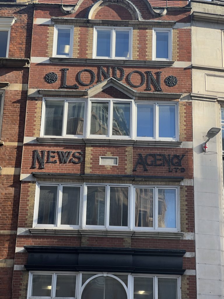 Image of a red brick three story building with the London News Agency signage.