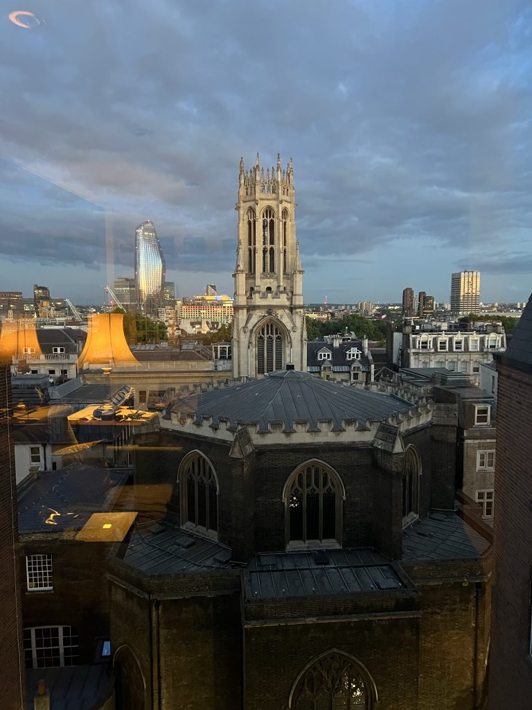Image of the view from the flat showing an old church and it's steeple in the foreground and the skyline of London with skyscrapers in the backgrround.