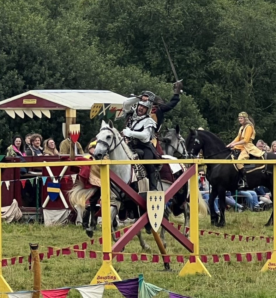 Two knights with swords in battle on the jousting field. In the background you see the fair maiden dressed in yellow and riding a black horse.