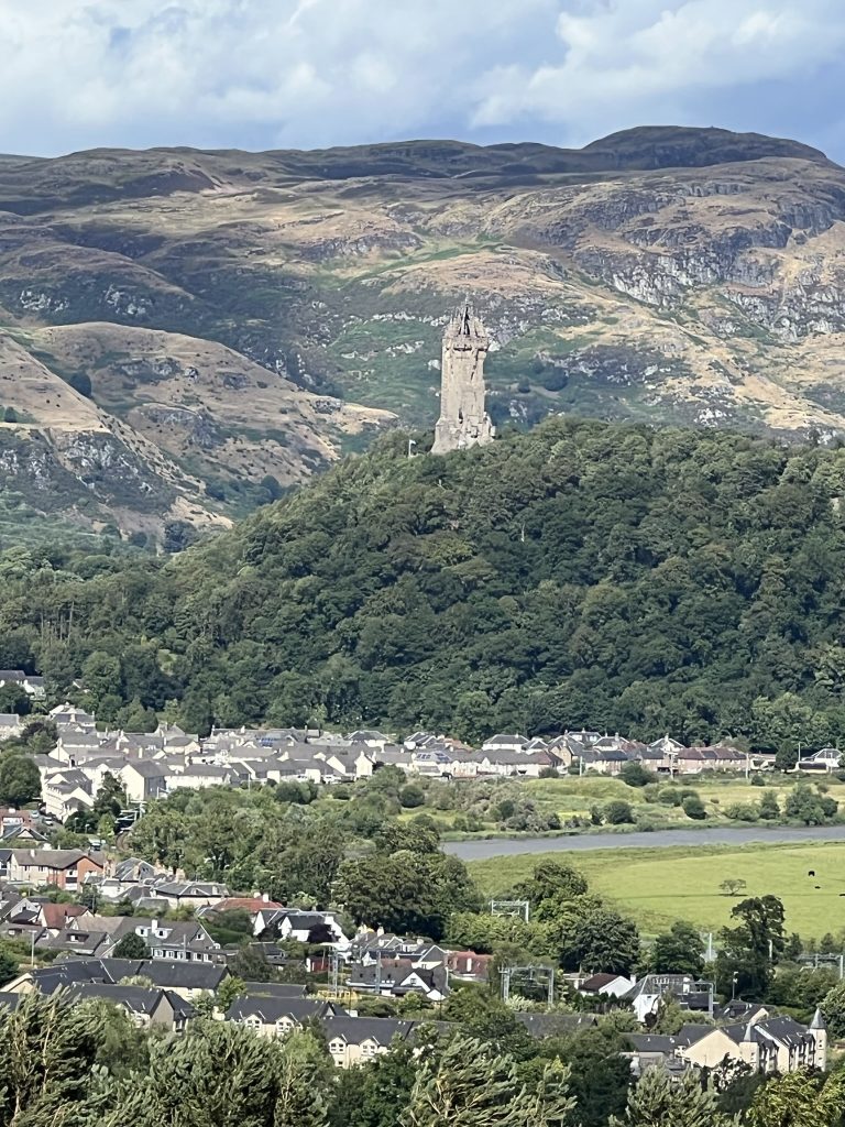 Looking east from the castle outer wall you can see the town of Stirling stretch out below.  On the next mountain over is the tall tower-like Wallace Monument.  Behind the monument are the rocky hills of Scotland. 