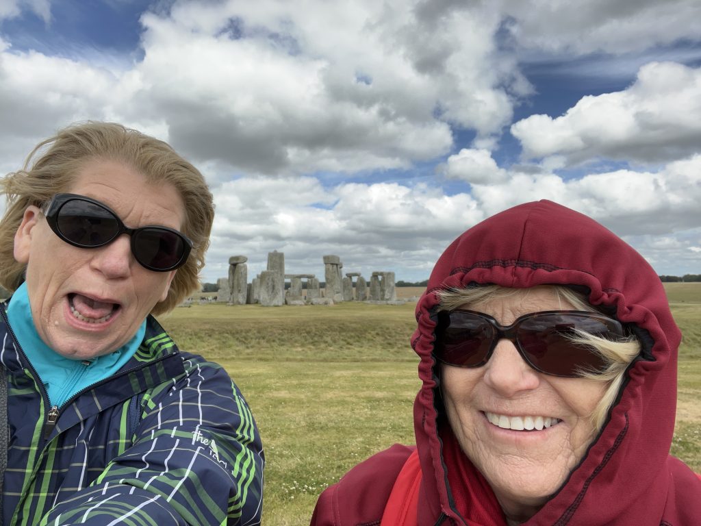 Jodi and Kay bundled up against the wind and chill with the stone circle behidn them.