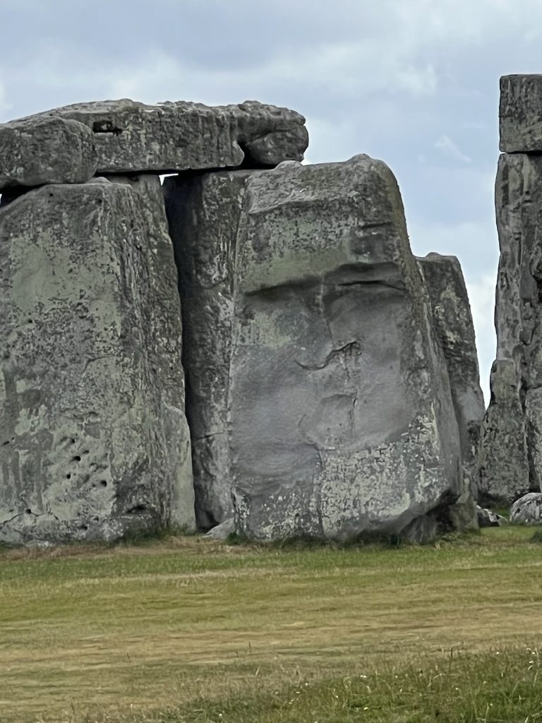 A close up of an upright stone that appears to have a large face "carved" into the stone.