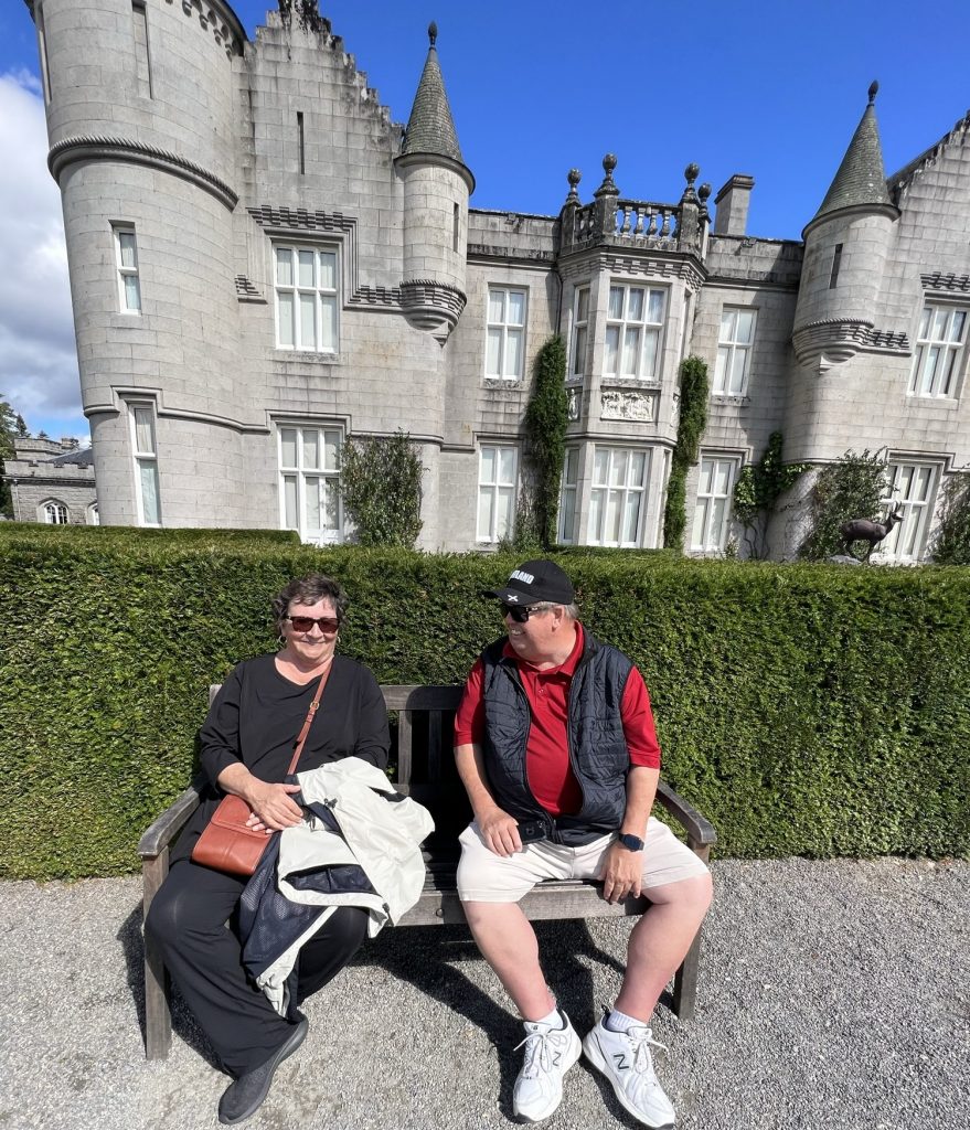 Kathy and Kenny sitting on a bench with the castle in the background. 